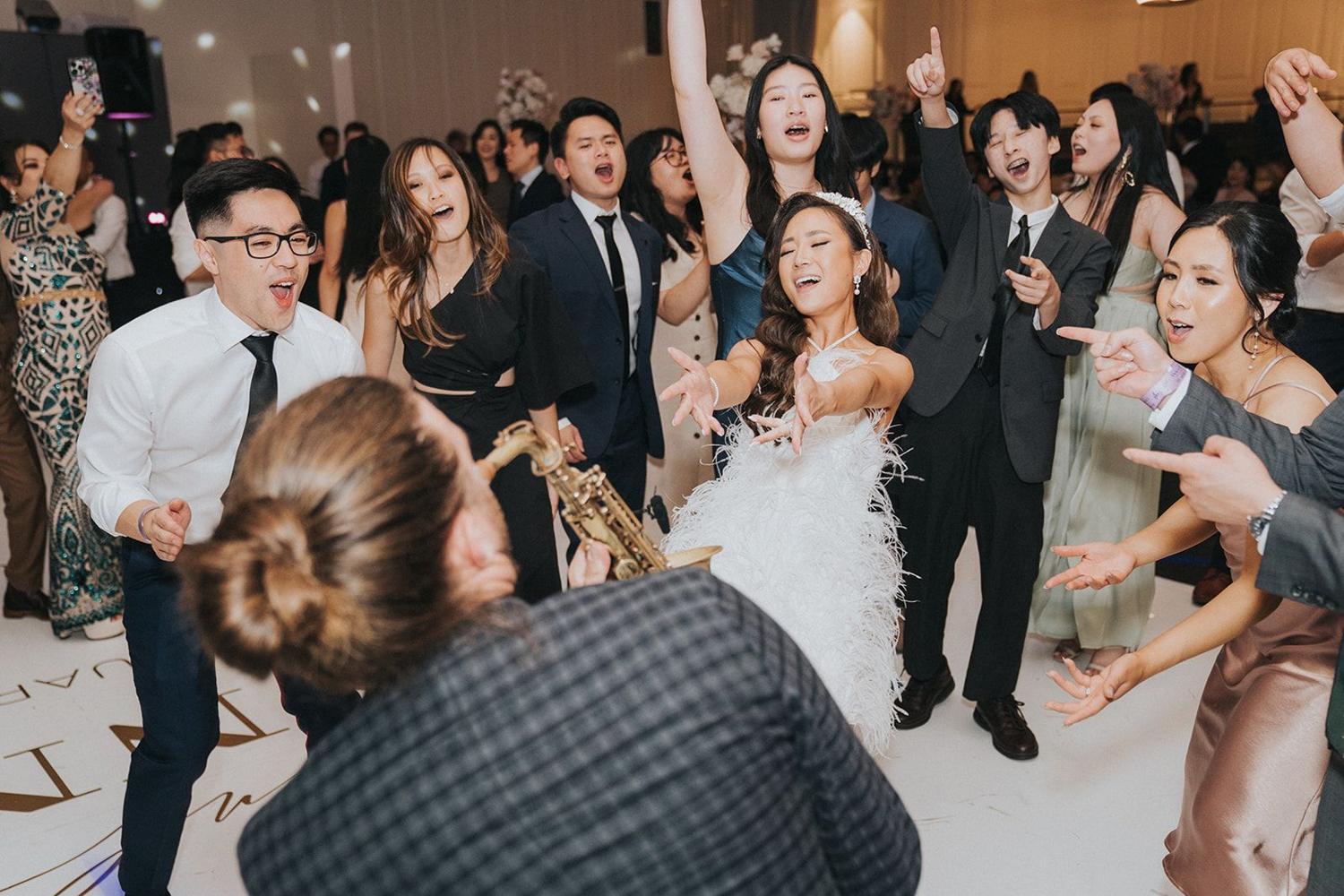 Bride and guests dancing together on a packed dance floor